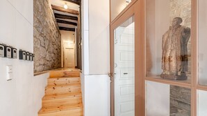 Eine Holztreppe führt zu einem Raum mit Steinwänden, einer weißen Tür und einer Statue.
