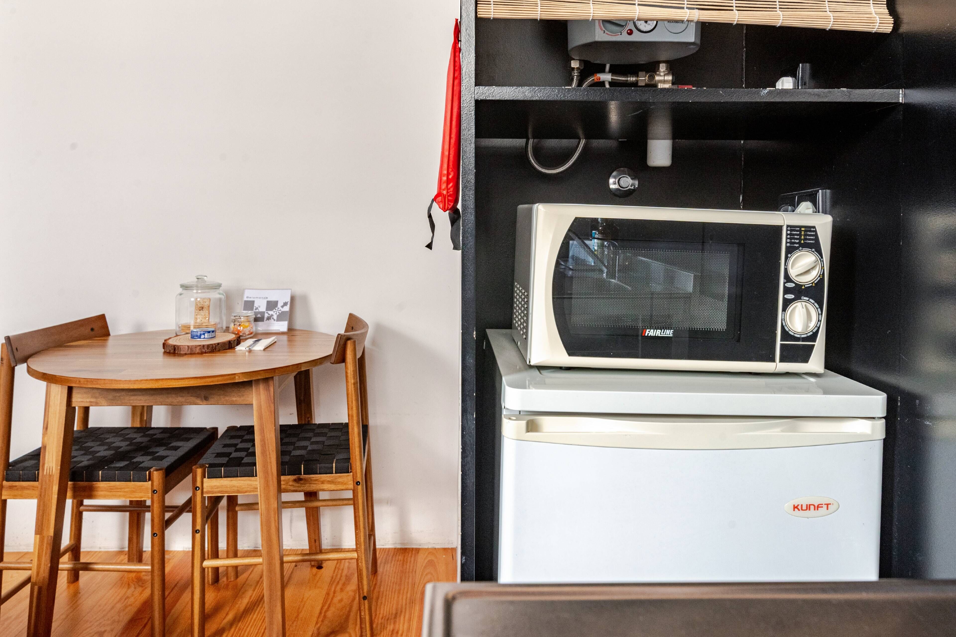 A compact kitchenette with a microwave and a small refrigerator.