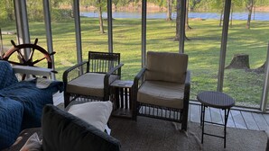 A covered patio with wicker furniture, a view of a lake, and a grassy area. - Peak Season! Arkansas River Cabin with Dock,White Bluff Views, Fishing & Sandbar (Tucker)