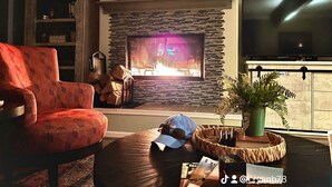 A living room with a fireplace, a television, and a red armchair. - Peak Season! Arkansas River Cabin with Dock,White Bluff Views, Fishing & Sandbar (Tucker)