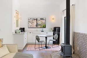 A compact kitchen with a dining area, a stove, and a large window. - Moonbeam Mountain - Stylish Suites + Hot Tub (Joshua Tree)