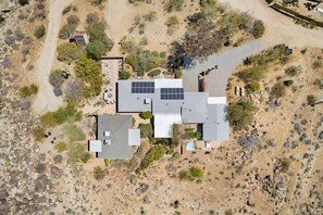 Una casa con techo de paneles solares, rodeada de vegetación desértica.