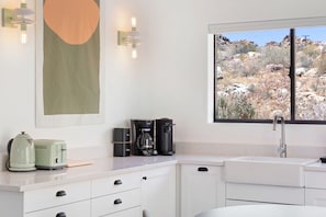 A kitchen with a window view of a rocky landscape, a coffee maker, and a toaster.