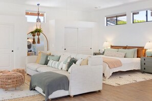 Un dormitorio con cama, mesitas de noche, un sofá y una planta colgante.