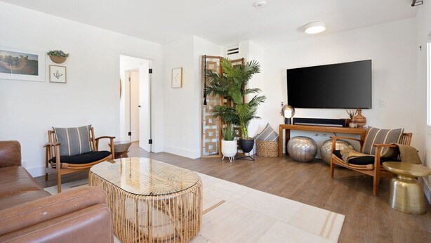 Ett modernt vardagsrum med en stor tv-skärm, ett runt soffbord i glas och två soffor.