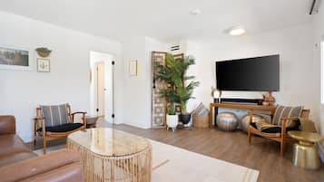 Un salon moderne avec un grand téléviseur à écran plat, une table basse ronde en verre et deux canapés.