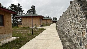 A row of wooden cabins with a stone wall on one side.