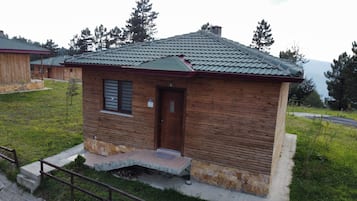Uma pequena cabana de madeira com telhado de telhas, uma porta e uma janela.