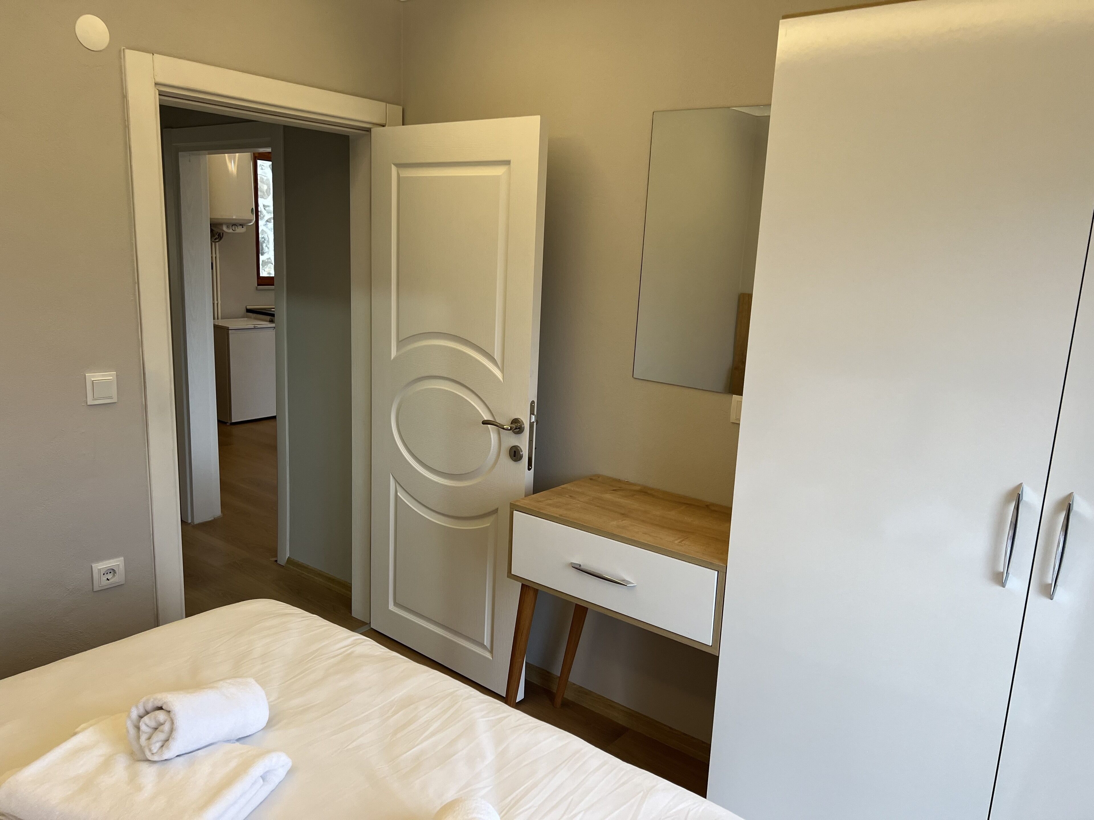 Habitación de hotel con cama, escritorio de madera, armario y baño a la vista a través de una puerta abierta.