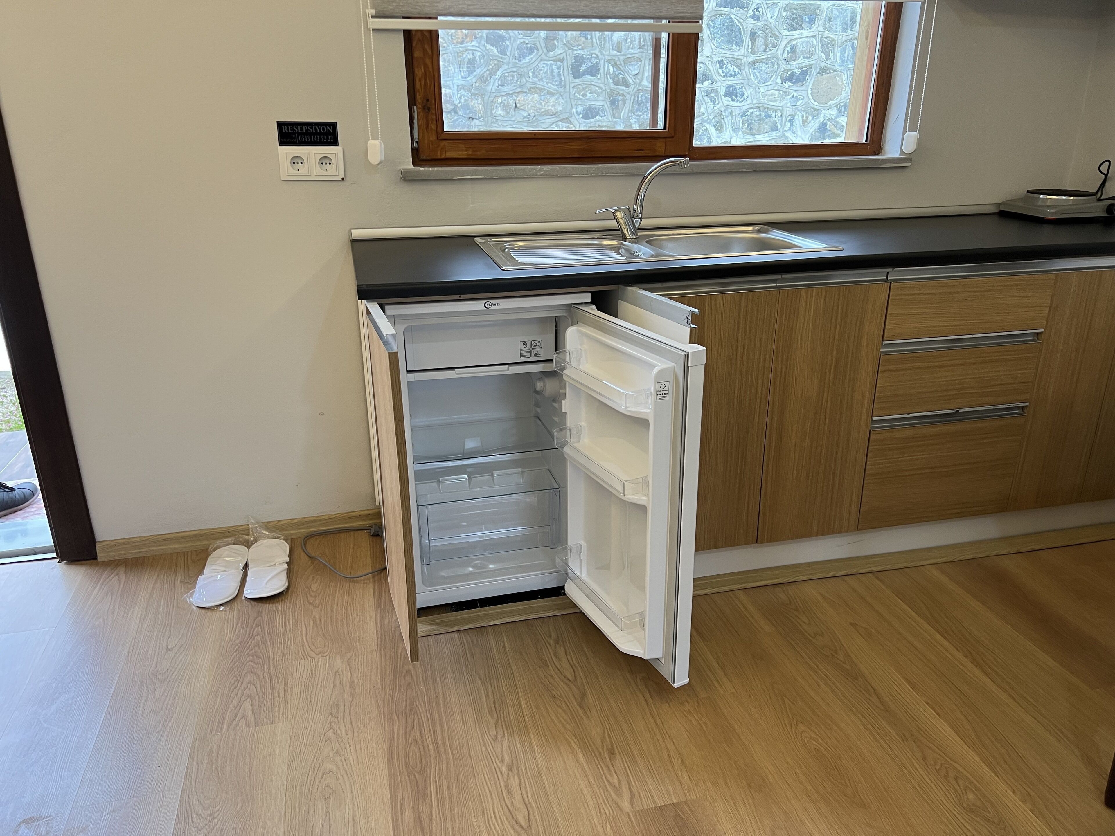 A kitchen with a built-in dishwasher, wooden cabinets, a sink, and a window above the sink.
