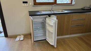 A kitchen with a built-in dishwasher, wooden cabinets, a sink, and a window above the sink.