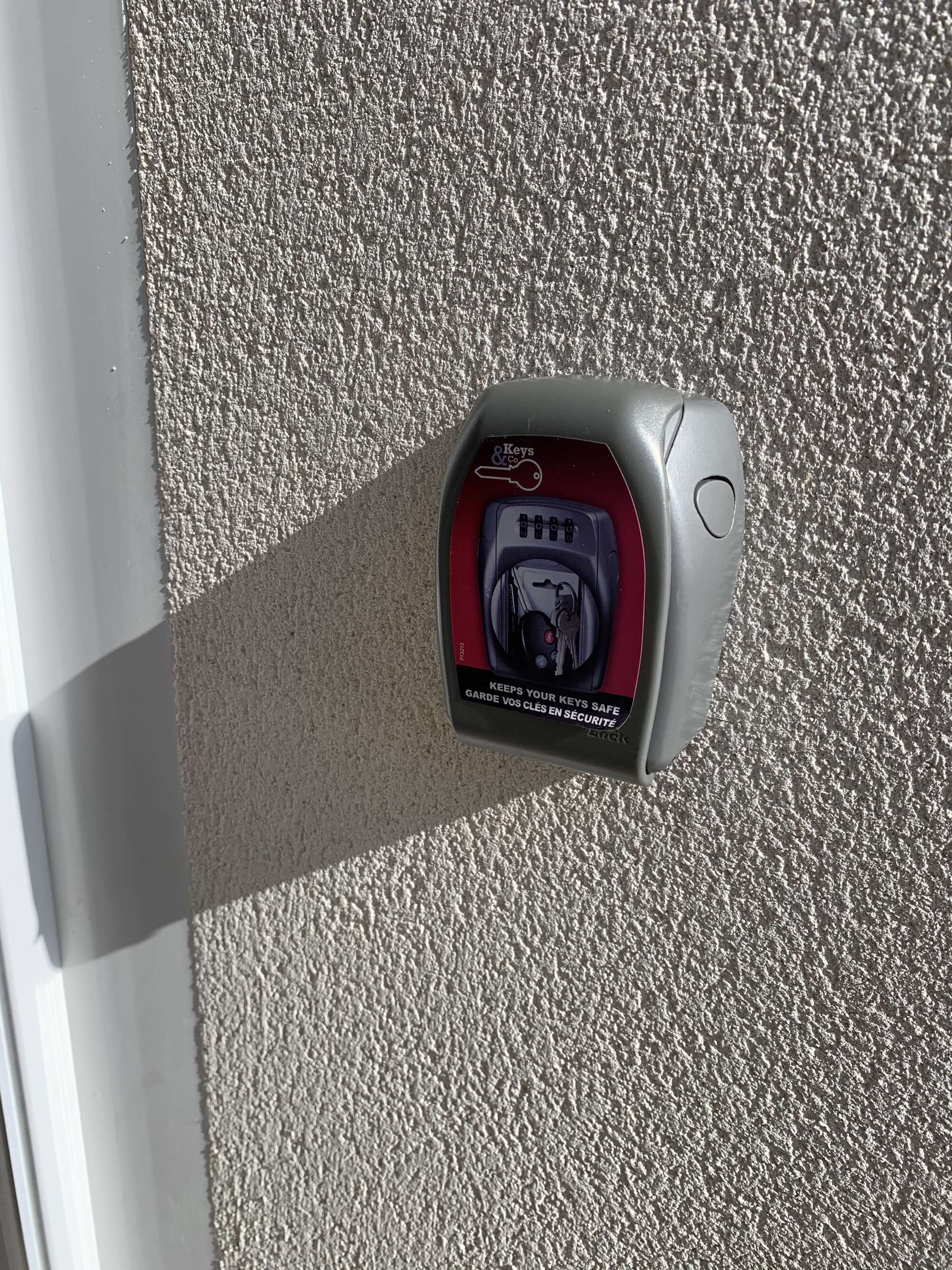 Un dispositivo de seguridad con teclado y mecanismo de cierre, fijado a una pared texturizada.