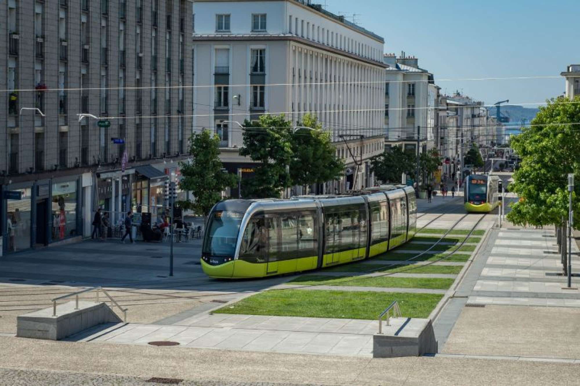 Eine moderne Straßenbahnhaltestelle mit einer eleganten, gelben Straßenbahn.