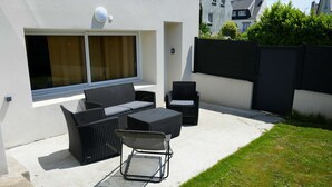 Un patio con mobiliario de mimbre, incluyendo un sofá, sillas y una mesita.