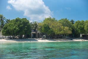 A beachfront property with a clear view of the ocean, a sandy beach, and lush green trees. - Thundi village and spa (Maalhos)