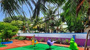 A playground with colorful play structures and a green mat. - Thundi village and spa (Maalhos)