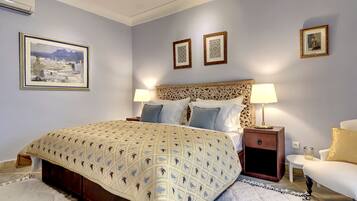 A neatly arranged bedroom with a large bed, two bedside tables with lamps, a decorative headboard, and framed artwork on the walls.