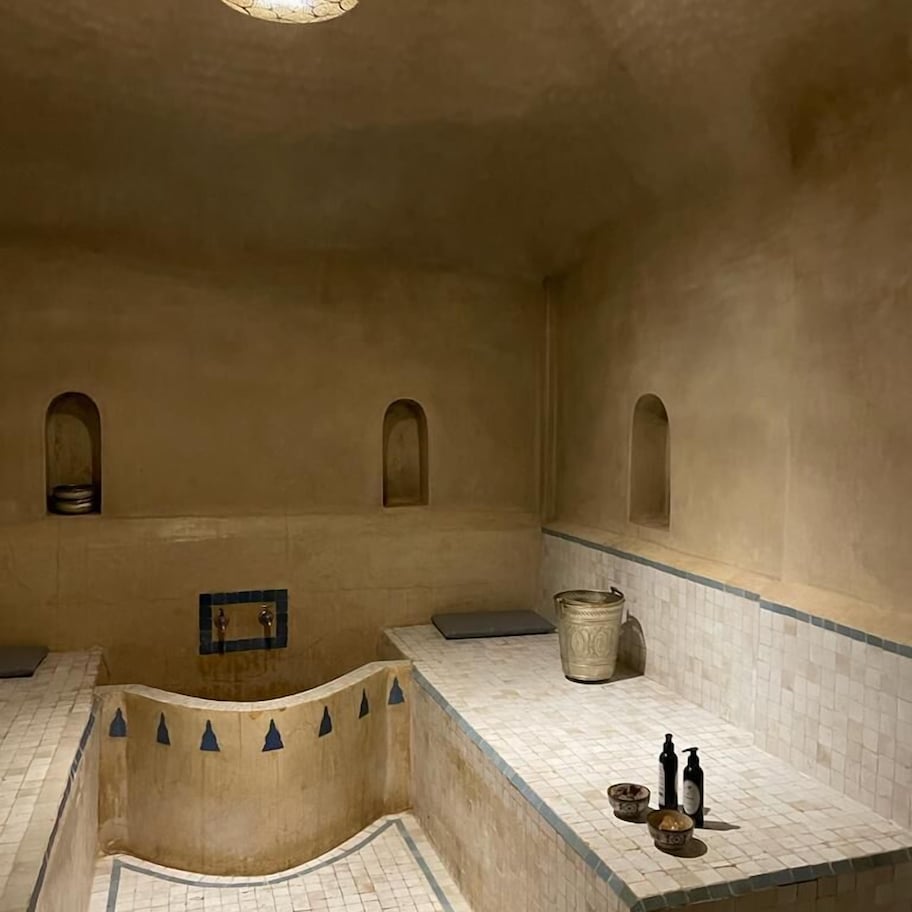 A room with a tiled floor, a central seating area, a small table, and a hanging light fixture.