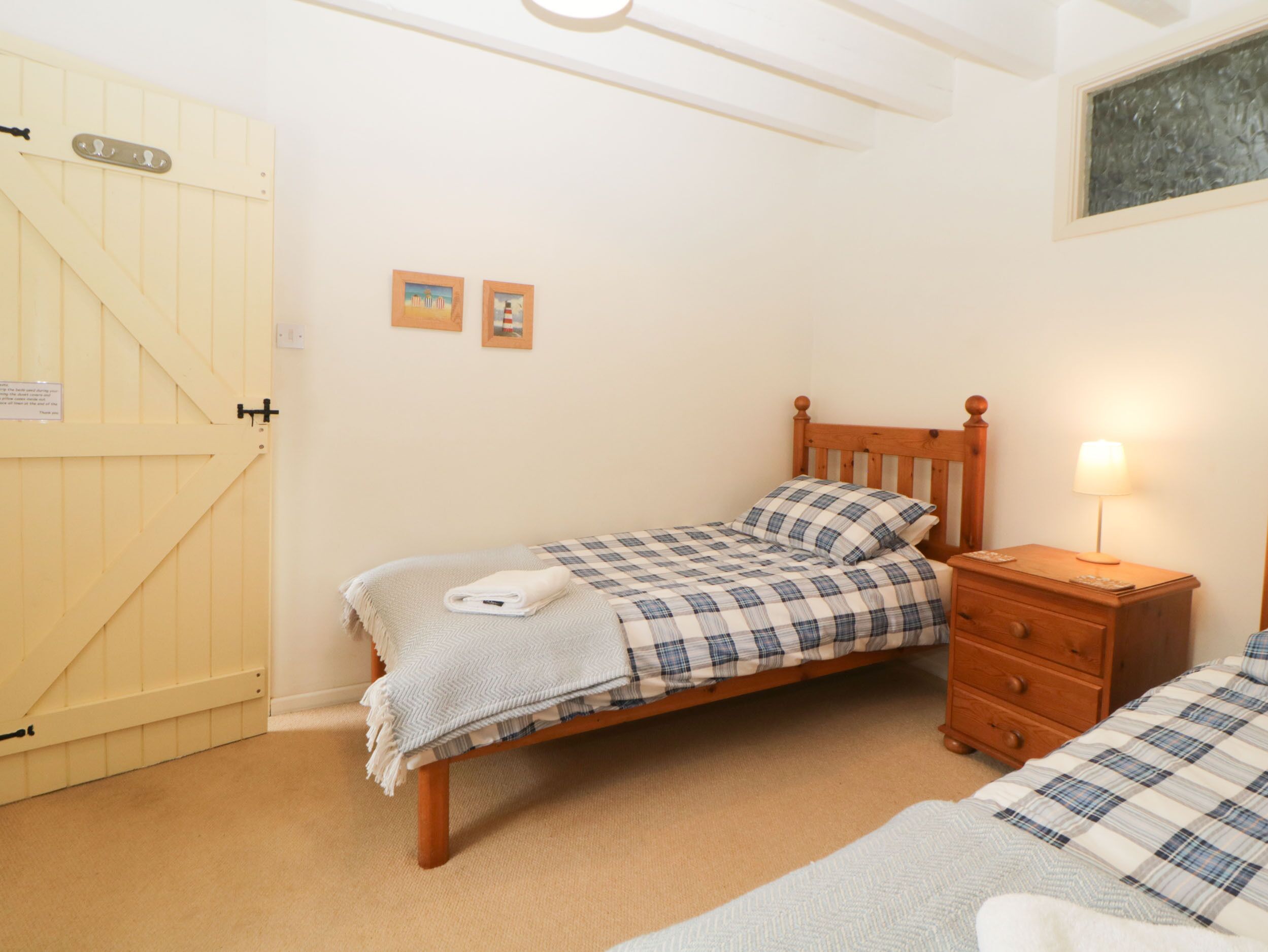 A bedroom with a single bed, a wooden nightstand, a lamp, and a door with a sign.