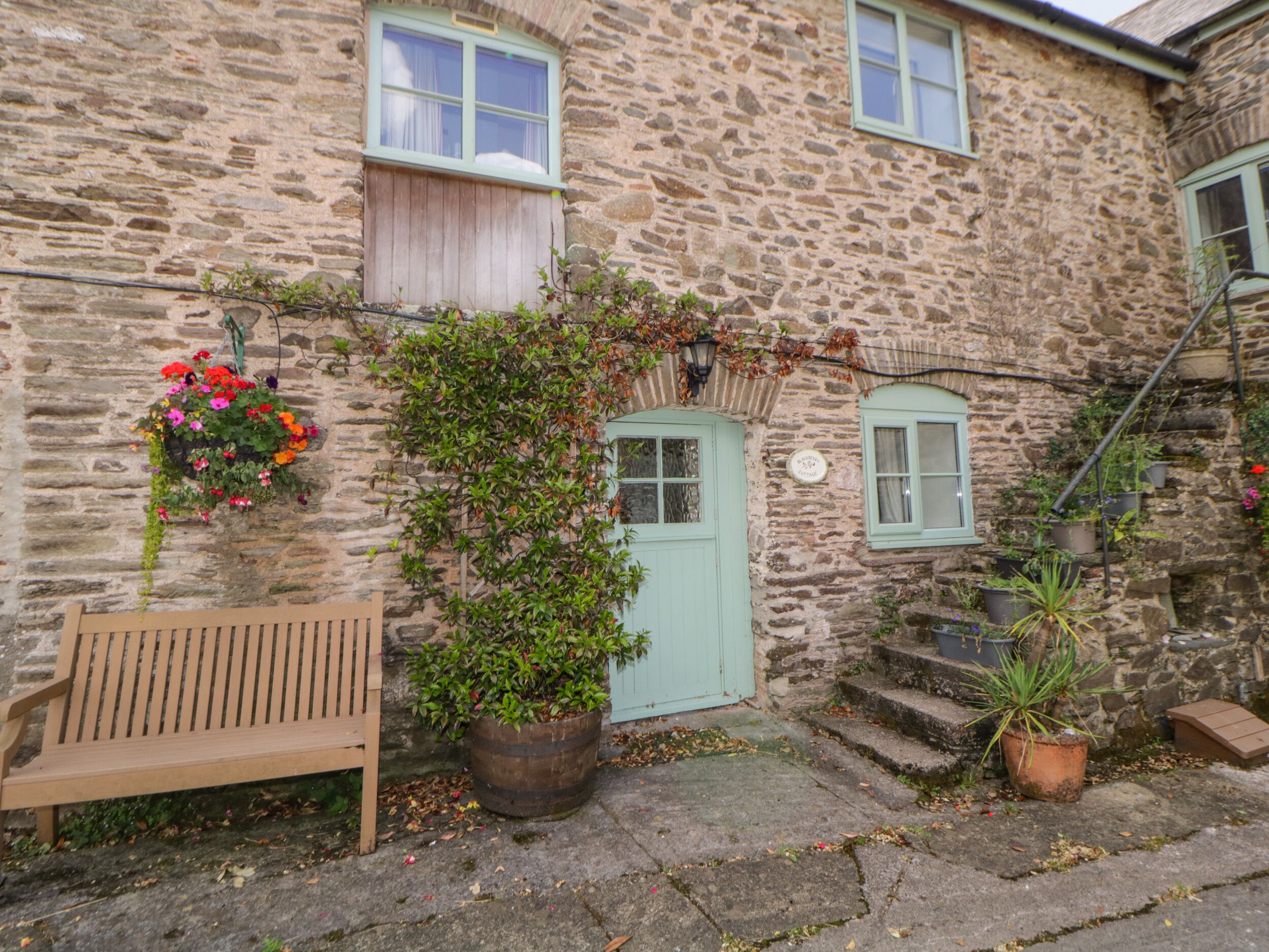 A stone building with a wooden bench, a door, and potted plants.