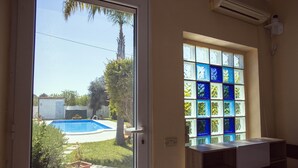 A room with a glass door leading outside, a small pool, and a window with colorful stained glass. - 3367 Villa Parco Grande by Perle di Puglia (Carovigno)