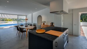 Een moderne keuken met een centraal eiland, een eethoek en uitzicht op een zwembad.