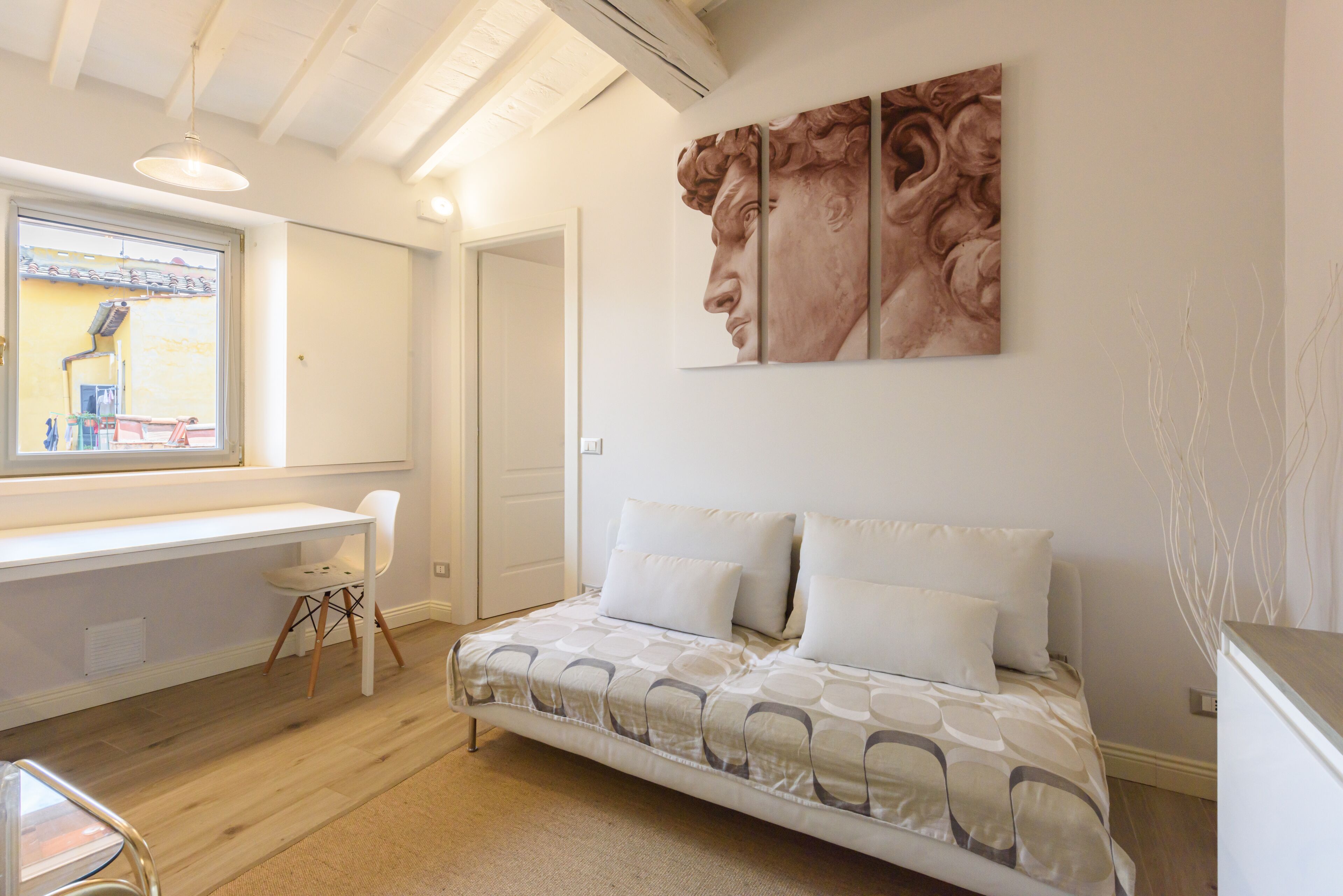 A bedroom with a bed, a desk, and a chair.