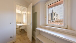 A modern bathroom with a shower, toilet, and sink. There is a window with a view of buildings outside. - Santa Croce Top by Mmega (Florence)