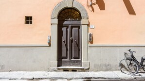 A building facade with a large arched entrance, a small window above the door, and a bicycle parked outside. - Santa Croce Top by Mmega (Florence)