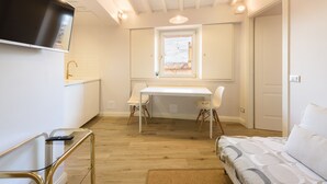 A compact room with a bed, a desk, and a TV mounted on the wall. - Santa Croce Top by Mmega (Florence)