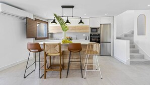 Una cucina moderna con un'isola centrale, sgabelli da bar e una lampada a sospensione.