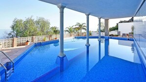 Una piscina con vista chiara sul mare, circondata da una recinzione bianca e palme.