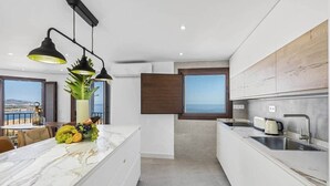 Una cucina moderna con un piano di lavoro in marmo, forno integrato e lavello. Si vede una finestra con vista sul mare.