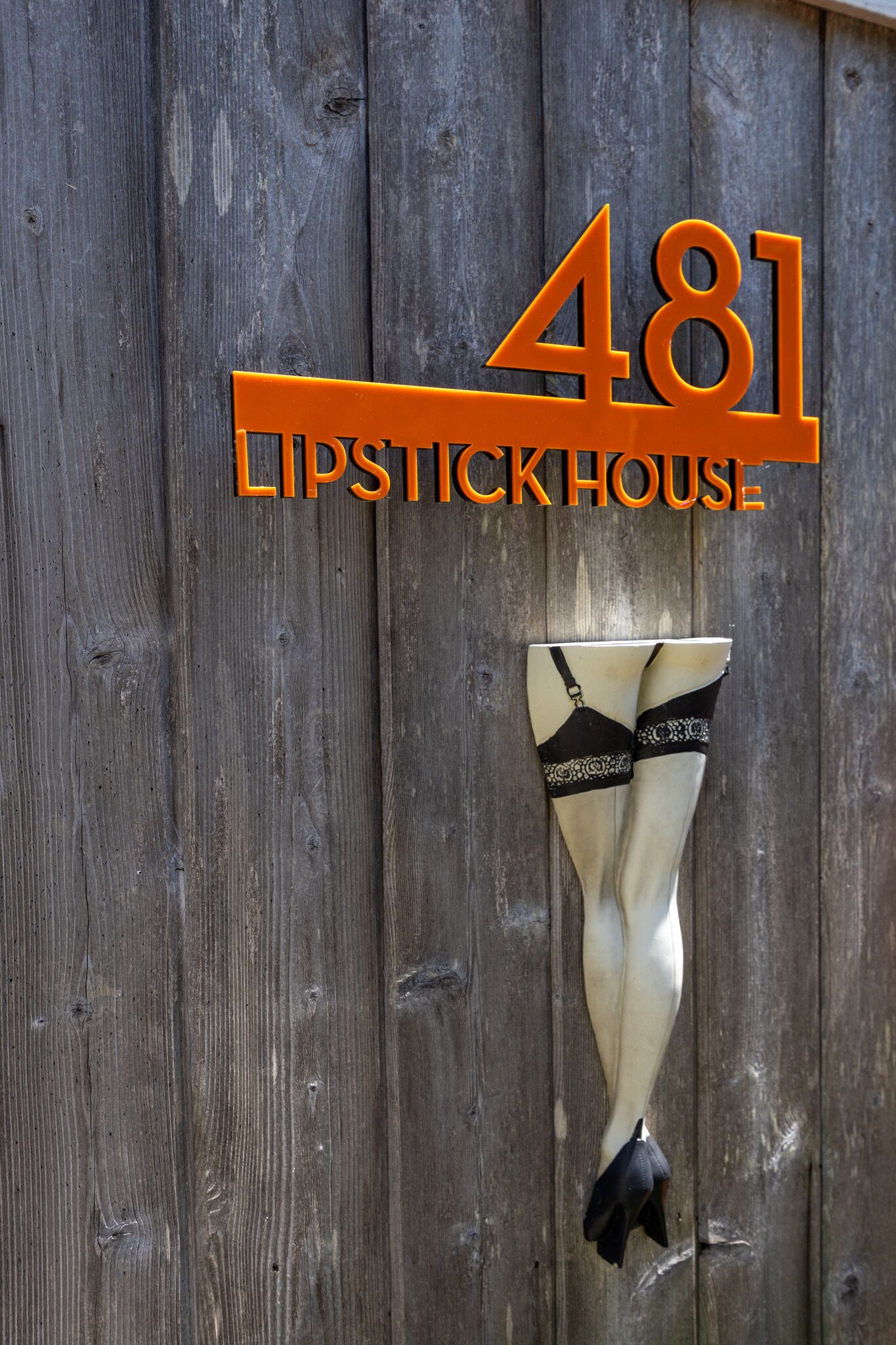 Een houten muur met het getal '481' en de tekst 'Lipstick House', wat een pand of locatie aanduidt.