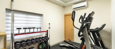 A gym with a weight bench, dumbbells, and a stationary bike.