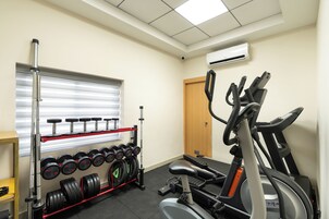Un gimnasio con una banca de pesas, mancuernas y una bicicleta estática.