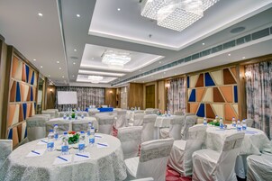 A conference room with round tables, chairs, and a whiteboard.