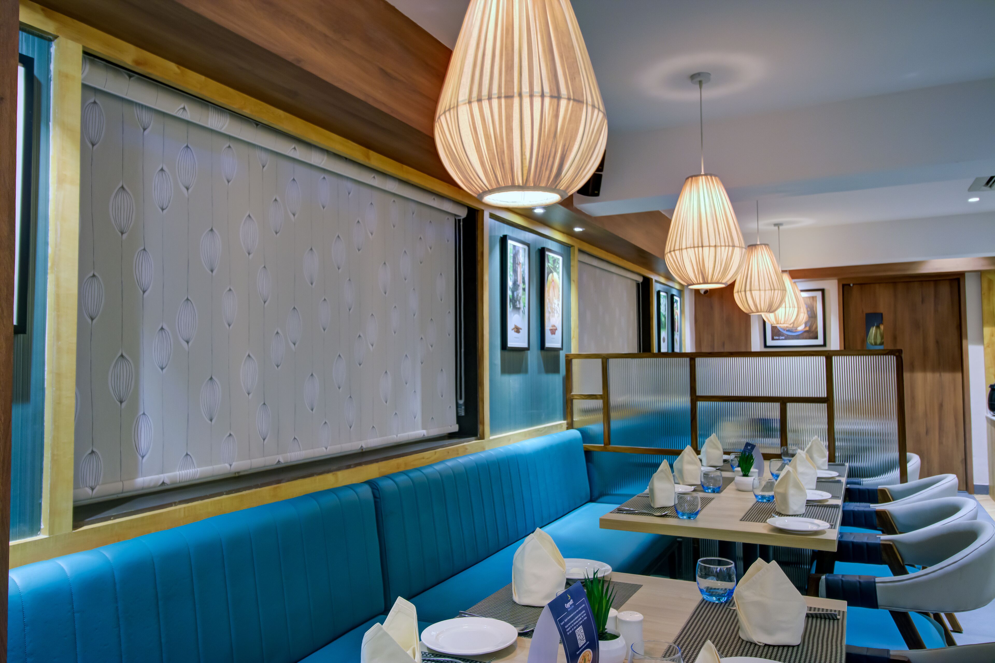 A restaurant with blue seating, wooden accents, and pendant lighting.