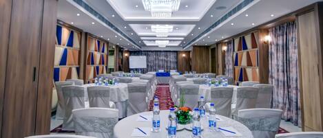 A conference room with round tables, chairs, and a stage.