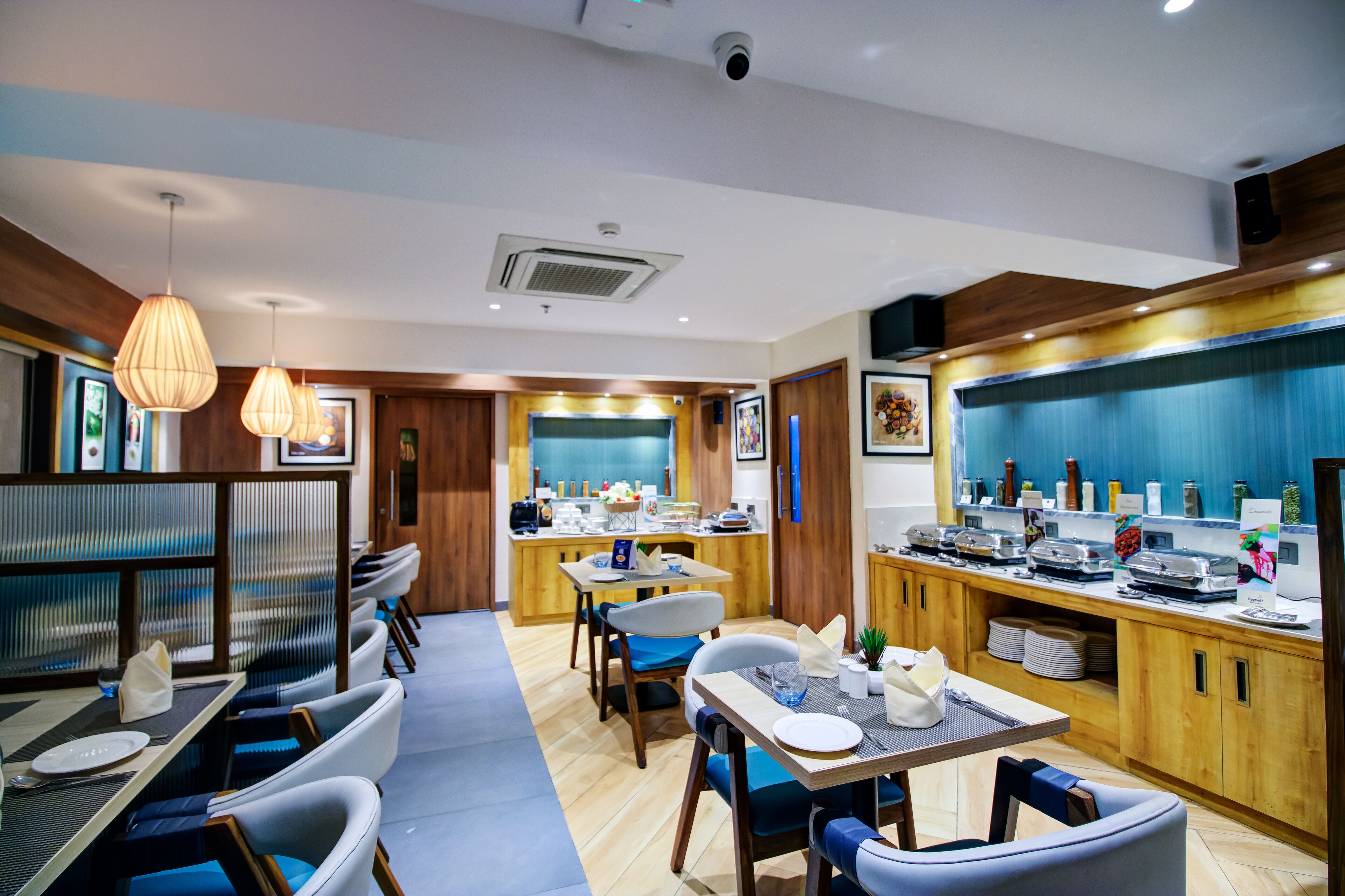 Uma área de refeições moderna com buffet, painéis de madeira e luminárias contemporâneas.
