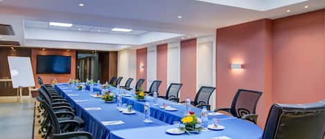 A conference room with a long table, chairs, and a whiteboard.