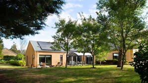 Una casa moderna con fachada de ladrillo, ventanas amplias y un patio con mobiliario exterior.