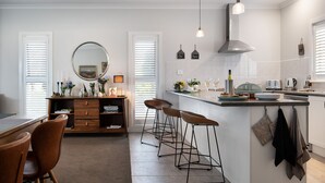 Una cocina moderna con una isla central, taburetes de bar y un comedor con mesa y sillas de madera.