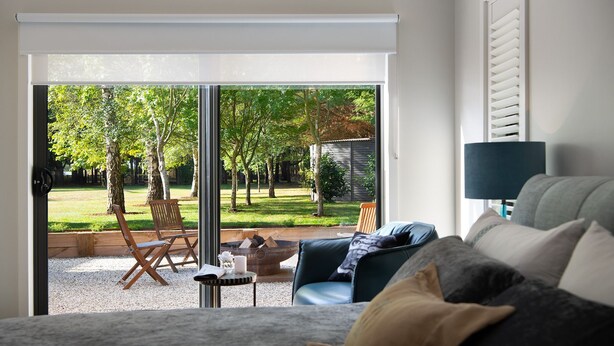 Una sala de estar moderna con un sofá, una mesa de centro y vistas a un jardín a través de un ventanal corredero.
