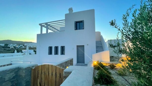 A modern white building with a wooden gate, a small window, and a door.