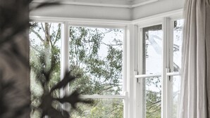 Sala de estar moderna com uma mesa de centro redonda, um sofá bege e uma janela ampla com vista para o verde.
