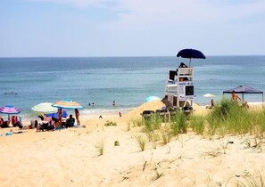 A beach with a lifeguard tower, umbrellas, and people enjoying the water.