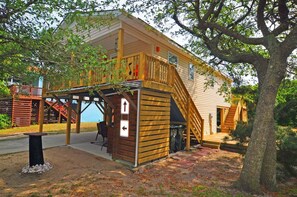 Un bâtiment en bois doté d’un porche couvert, d’un escalier et d’un petit espace extérieur aménagé pour s’asseoir.
