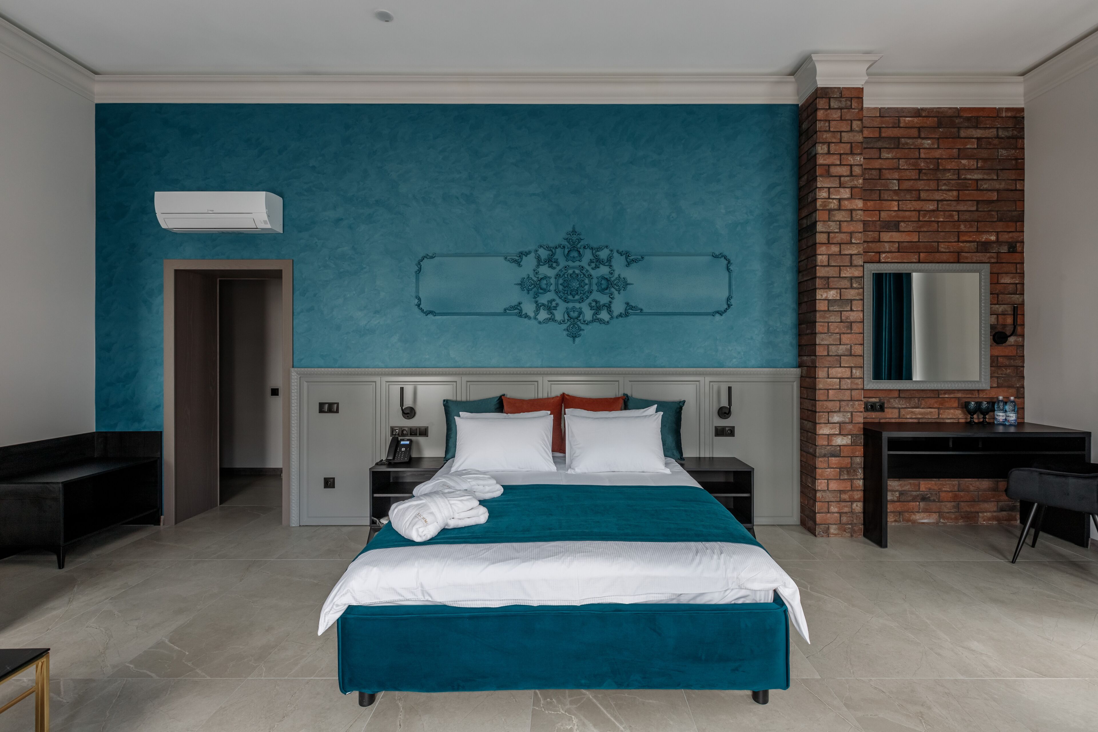 Hotelkamer met een groot bed, een bureau, een spiegel, een kledingkast en een deur naar de badkamer.