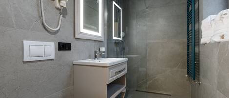 Ein modernes Badezimmer mit Dusche, Waschtisch und Spiegel sowie einem Handtuchhalter.